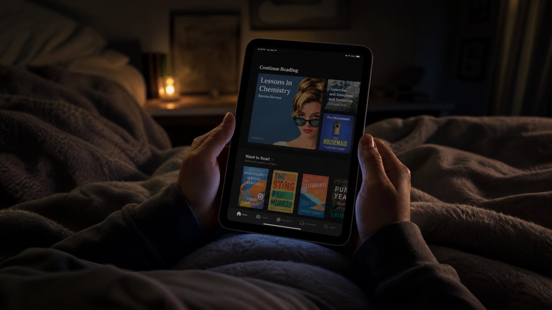薄暗いベッドの中で両手で iPad mini を持ち、Kindle の読書ライブラリを開いてくつろぐ夜の風景